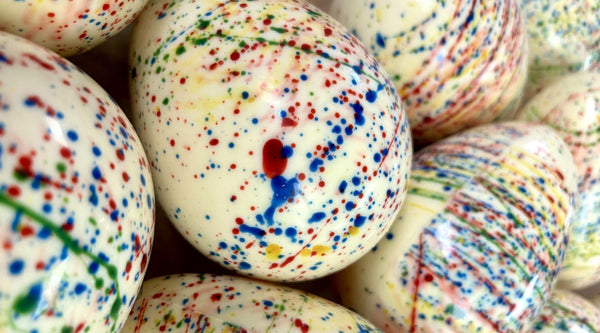 A selection of white chocolate Easter Eggs decorated with rainbow splatter