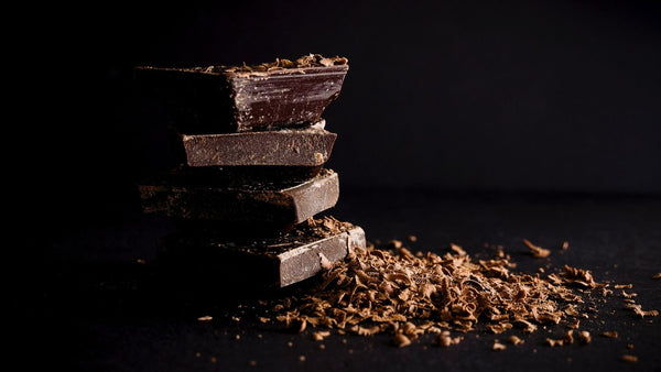 A stack of dark chocolate squares surrounded by chocolate shavings