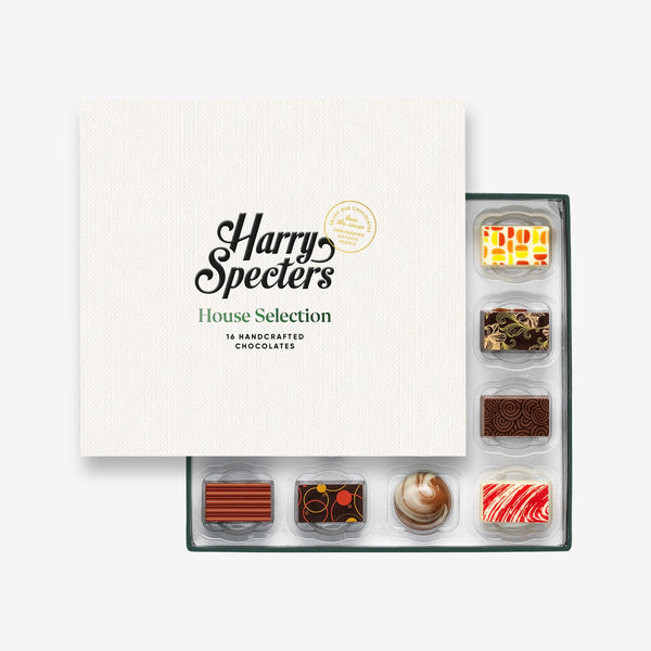 A box of 16 artisan chocolates by Harry Specters including Happy Holidays themed designs partially covered by a box lid 
